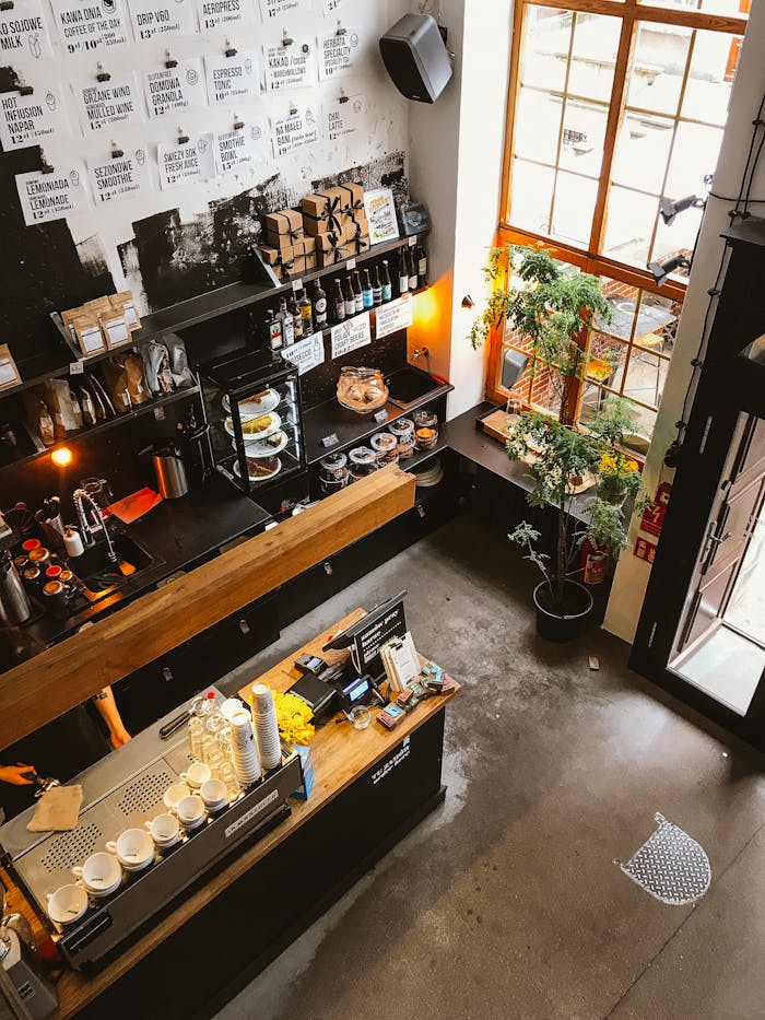 High angle view of a modern coffee shop interior with a wooden counter and cozy furnishings, ideal for business and leisure.